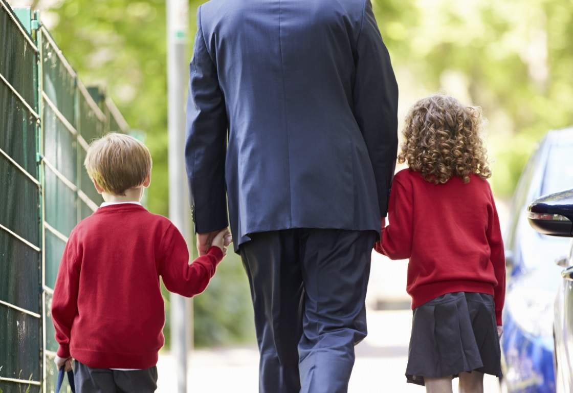 Large image-Father Walking to School With Children on the Way to Work. A father walking with children outdoors on the way to school, representing family routine and daily care.